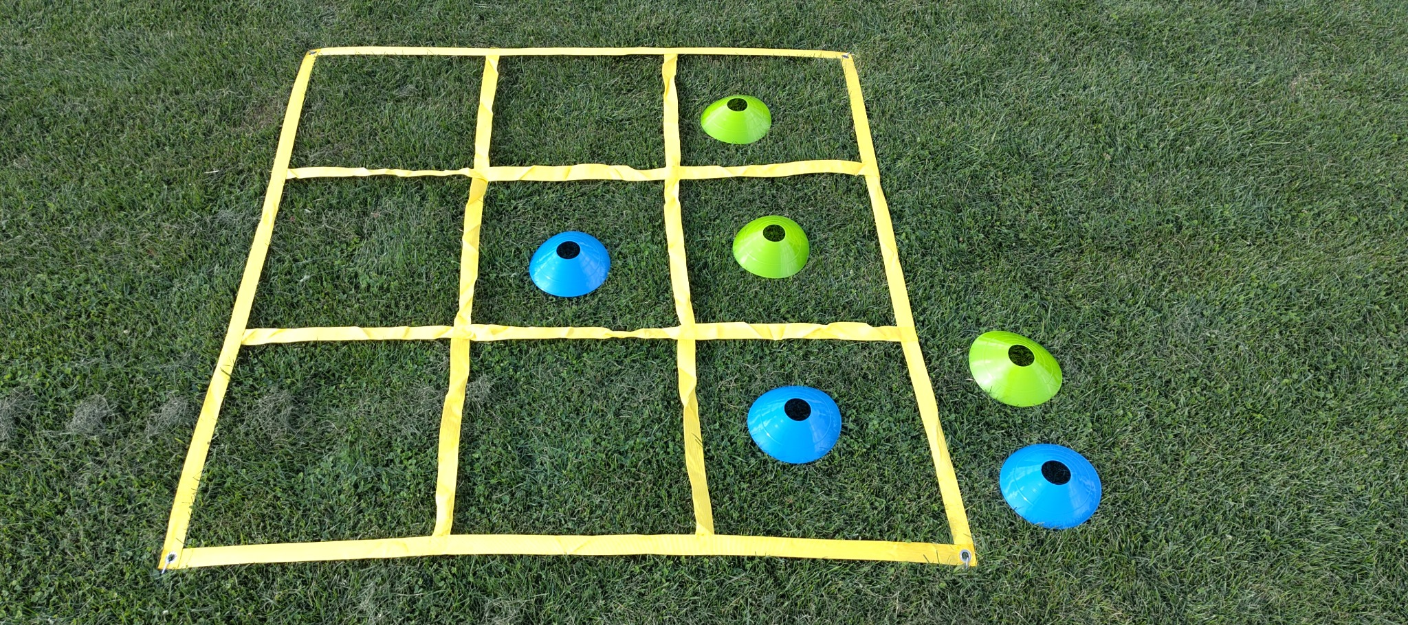 Het 3 × 3-speelveld met blauwe en groene dopjes voor 3 op een rij!